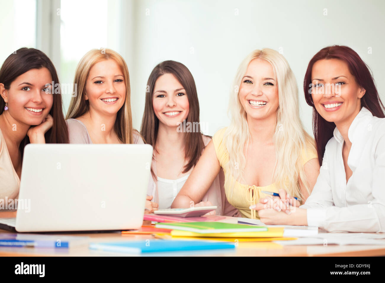 Group of student girls studying with their professor and smiling and looking at the camera. Stock Photo