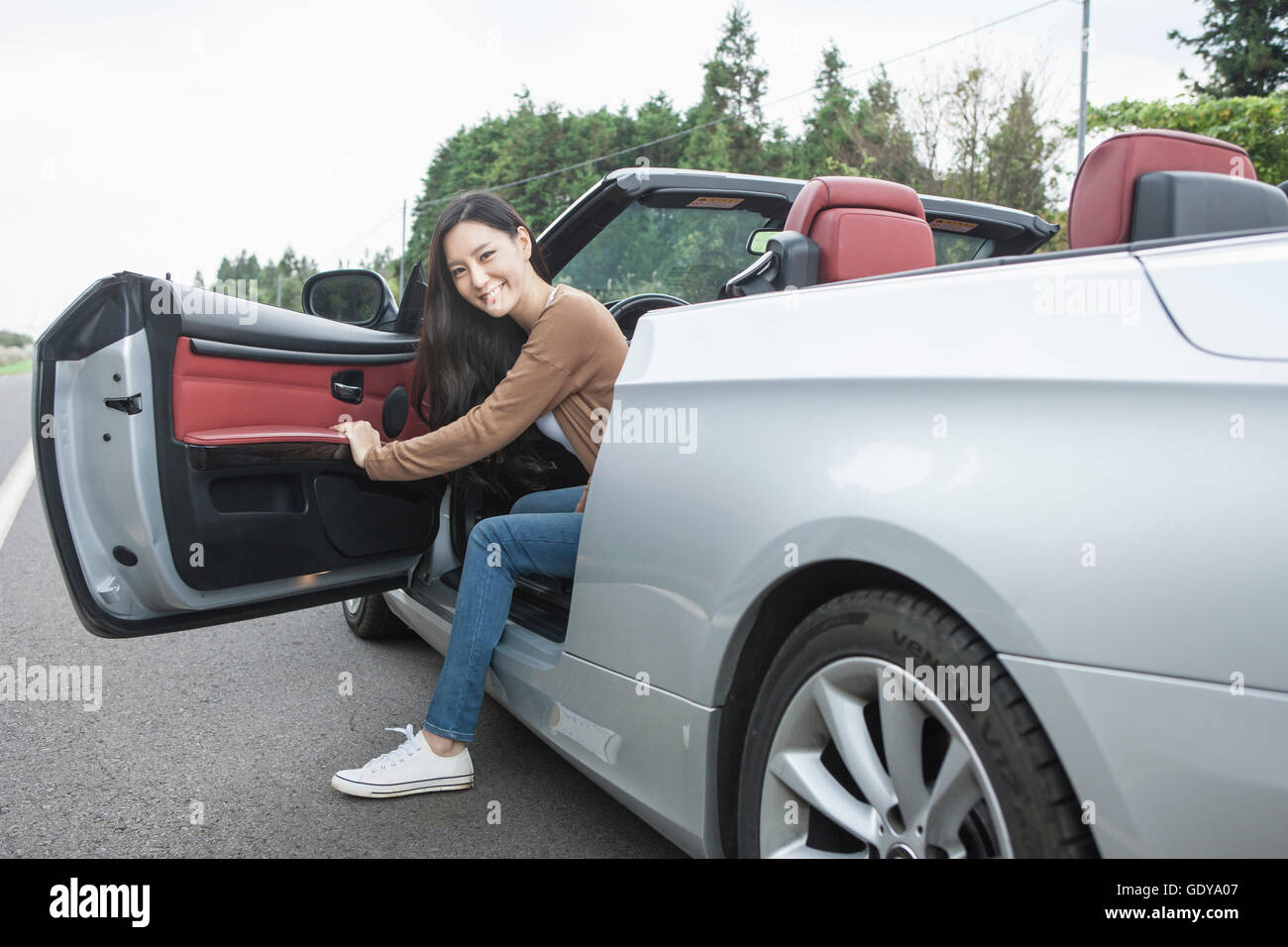 Young smiling woman getting out of a car Stock Photo Alamy