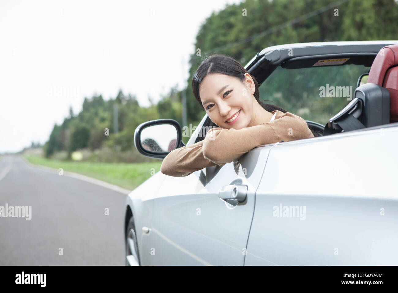 Portrait of young smiling woman looking out of window in a car Stock ...