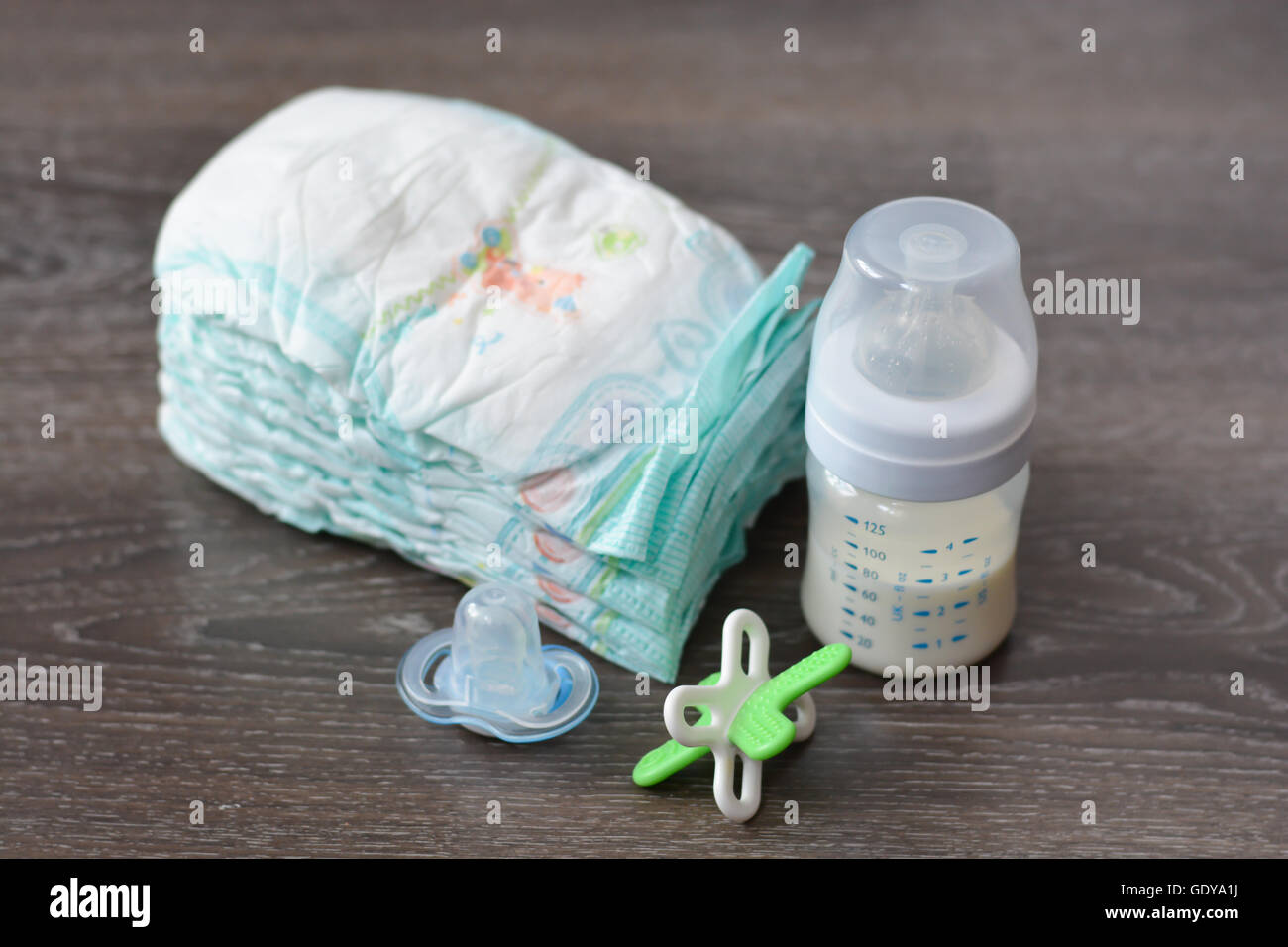 Diapers, baby milk bottle and a pacifier on wooden floor Stock Photo