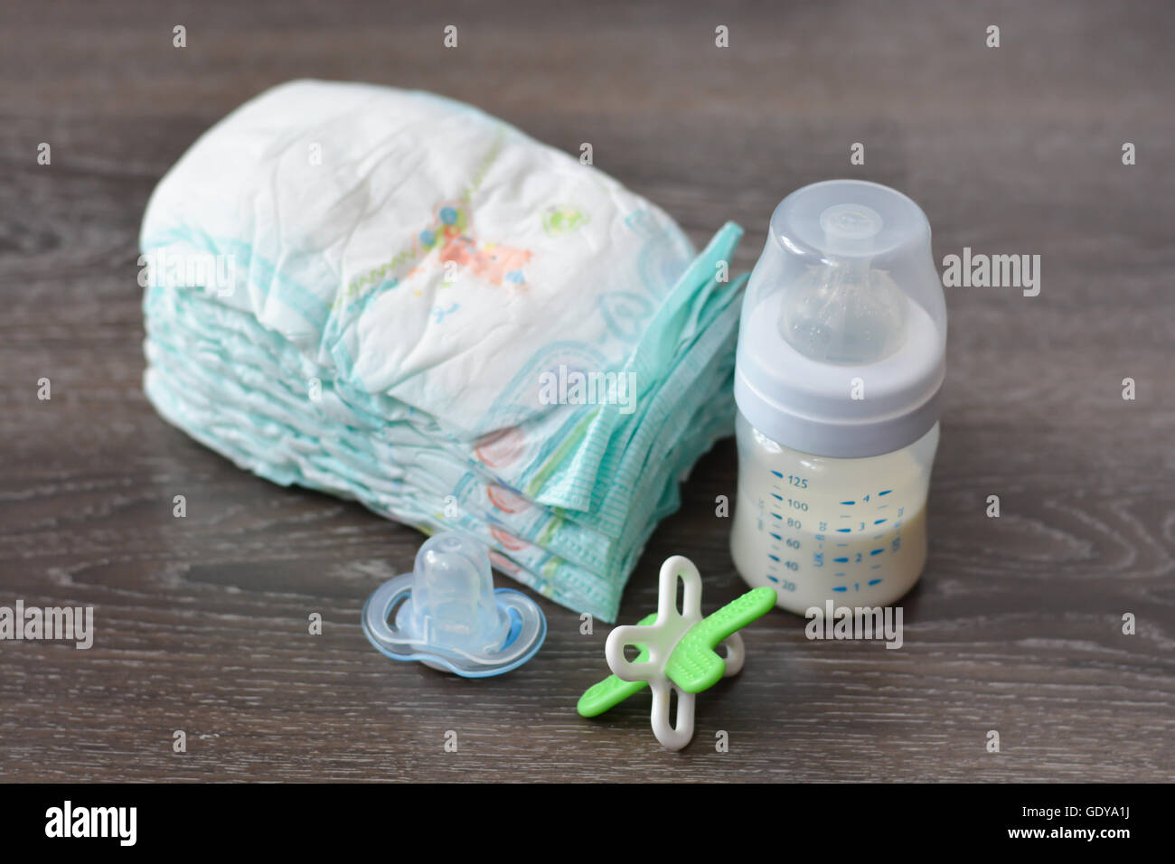 Diapers, baby milk bottle and a pacifier on wooden floor Stock Photo ...