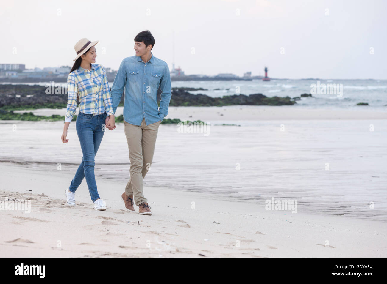 Young smiling couple walking hand in hand at beach Stock Photo - Alamy
