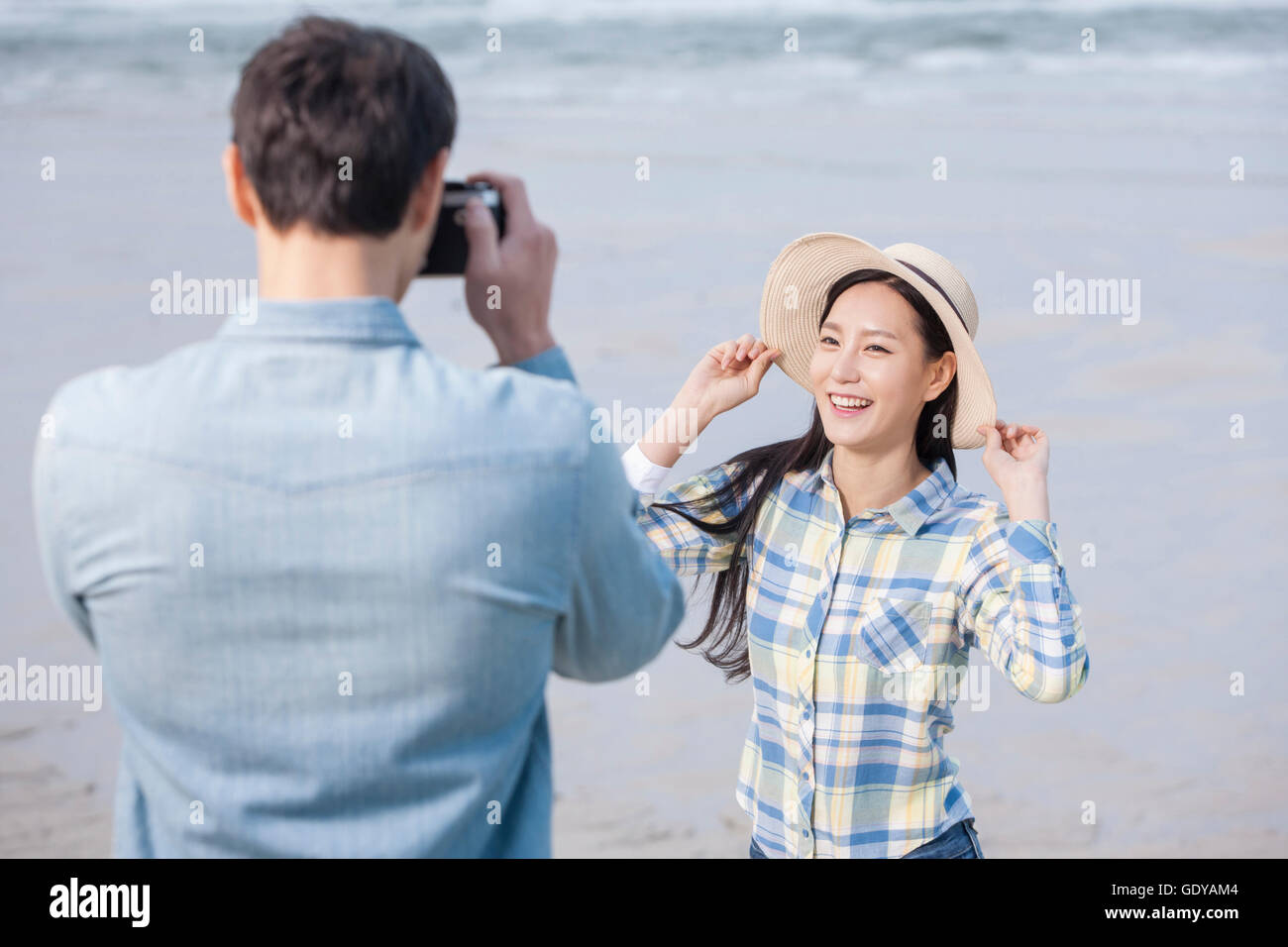 Portrait of young smiling couple posing and taking a picture against sea Stock Photo