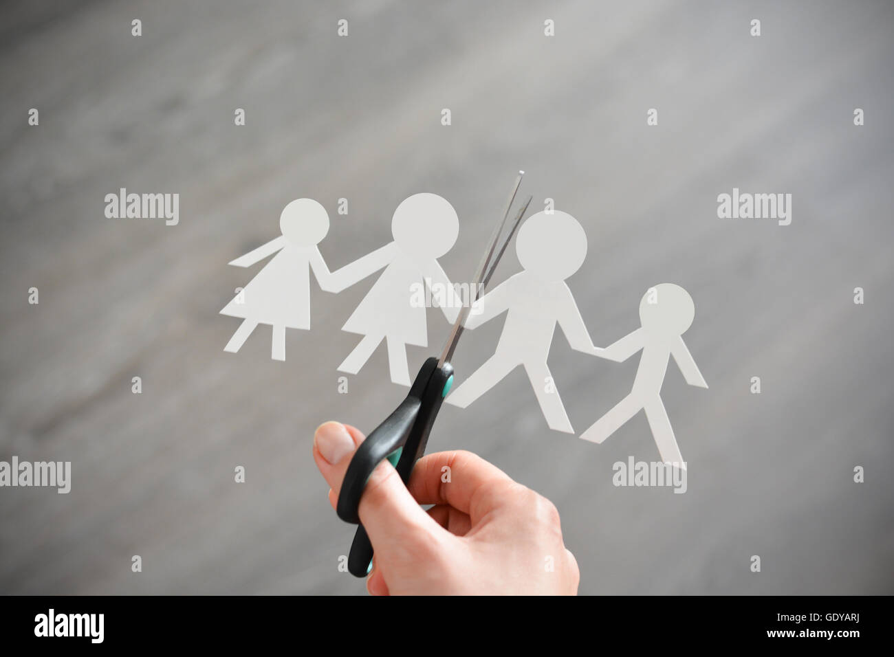 Family divorce concept with human paper shapes and scissors suggesting relationship problems Stock Photo