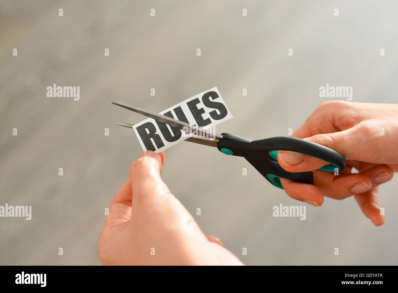 Woman hands cutting with scissors a printout reading 'RULES' Stock Photo