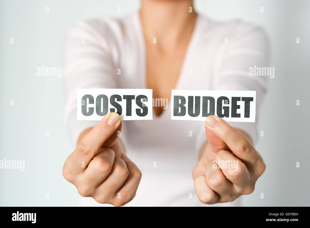Budget planning concept with woman hands holding two printout with cost and budget words Stock Photo