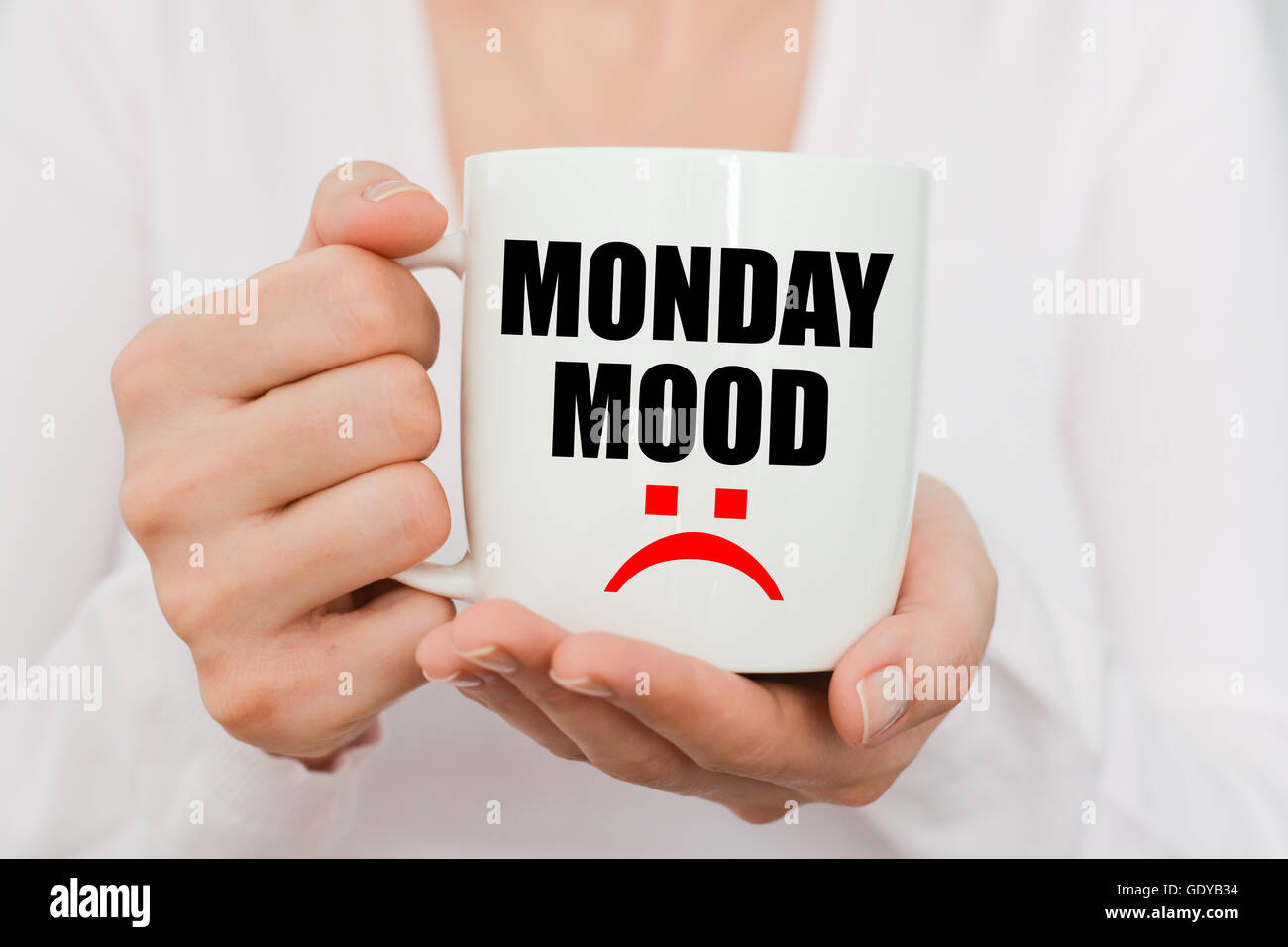 Monday mood with sad symbol on white coffee cup held by a woman Stock Photo