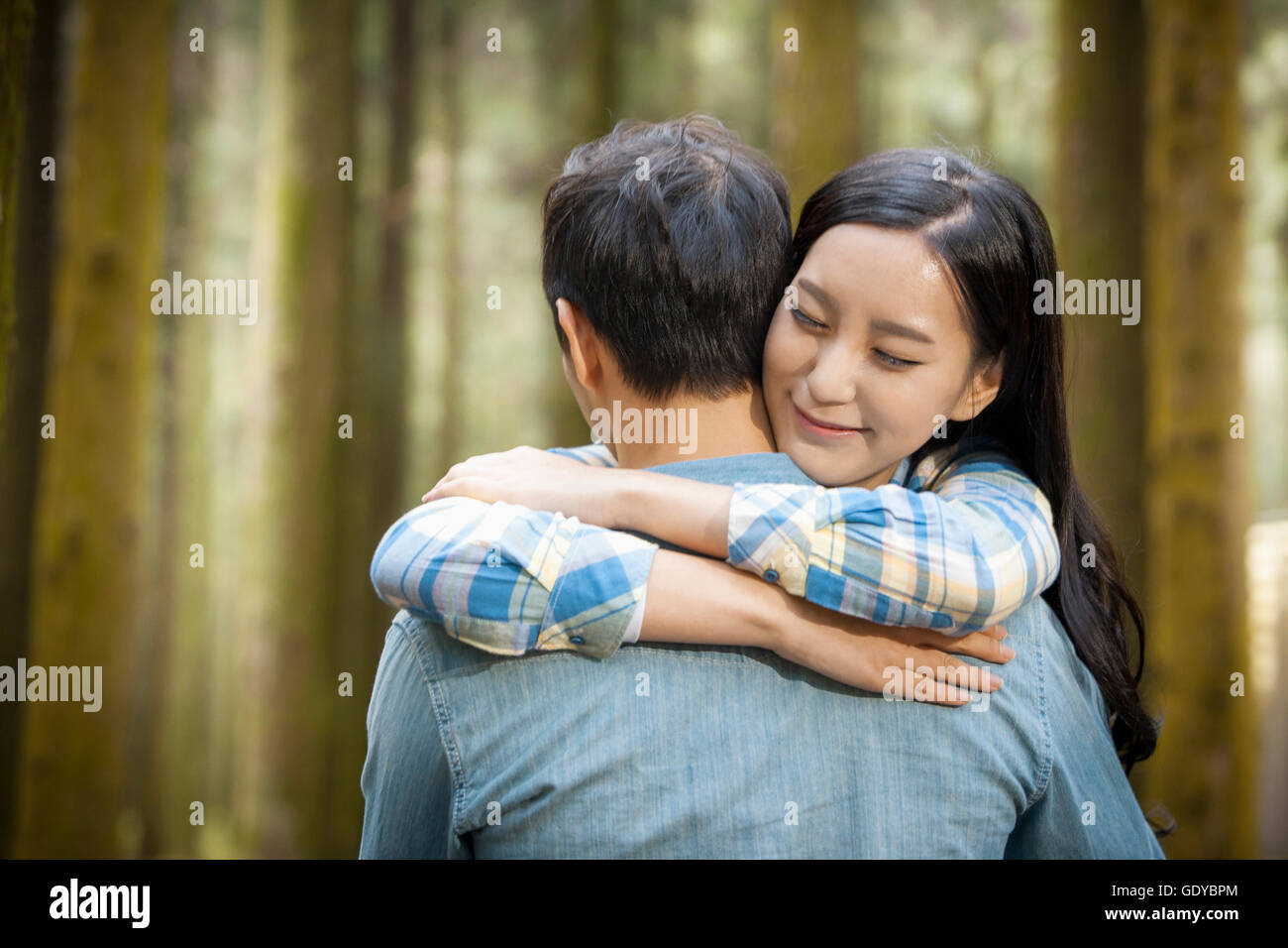 Portrait of young smiling woman hugging a man with her eyes closed ...