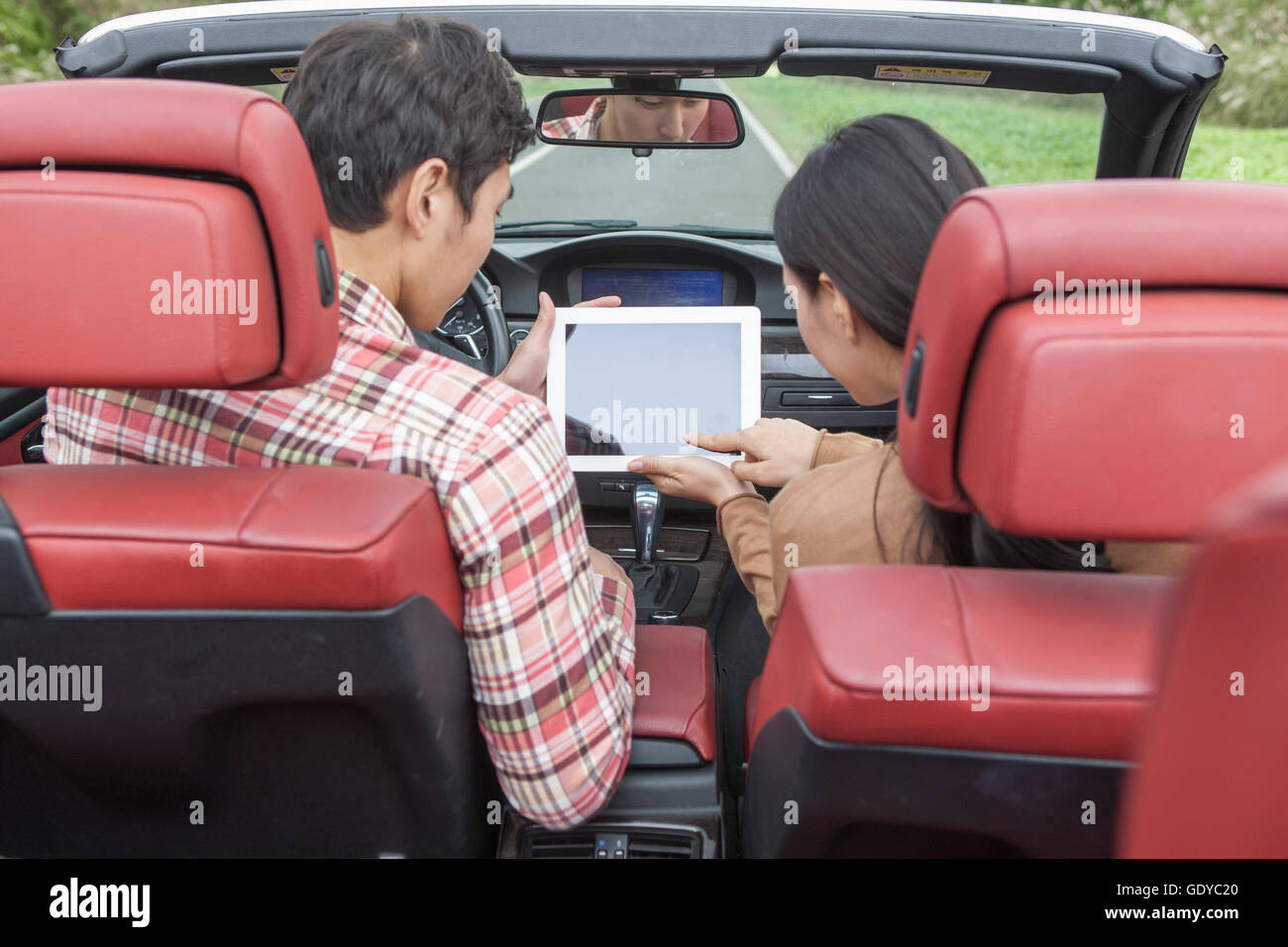 Back of young couple in a car using a tablet Stock Photo