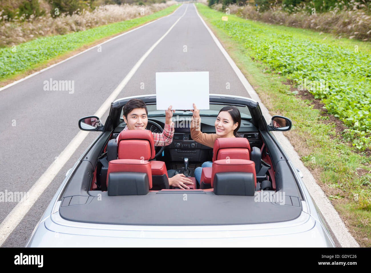Young smiling couple in a car holding a paper looking back Stock Photo ...