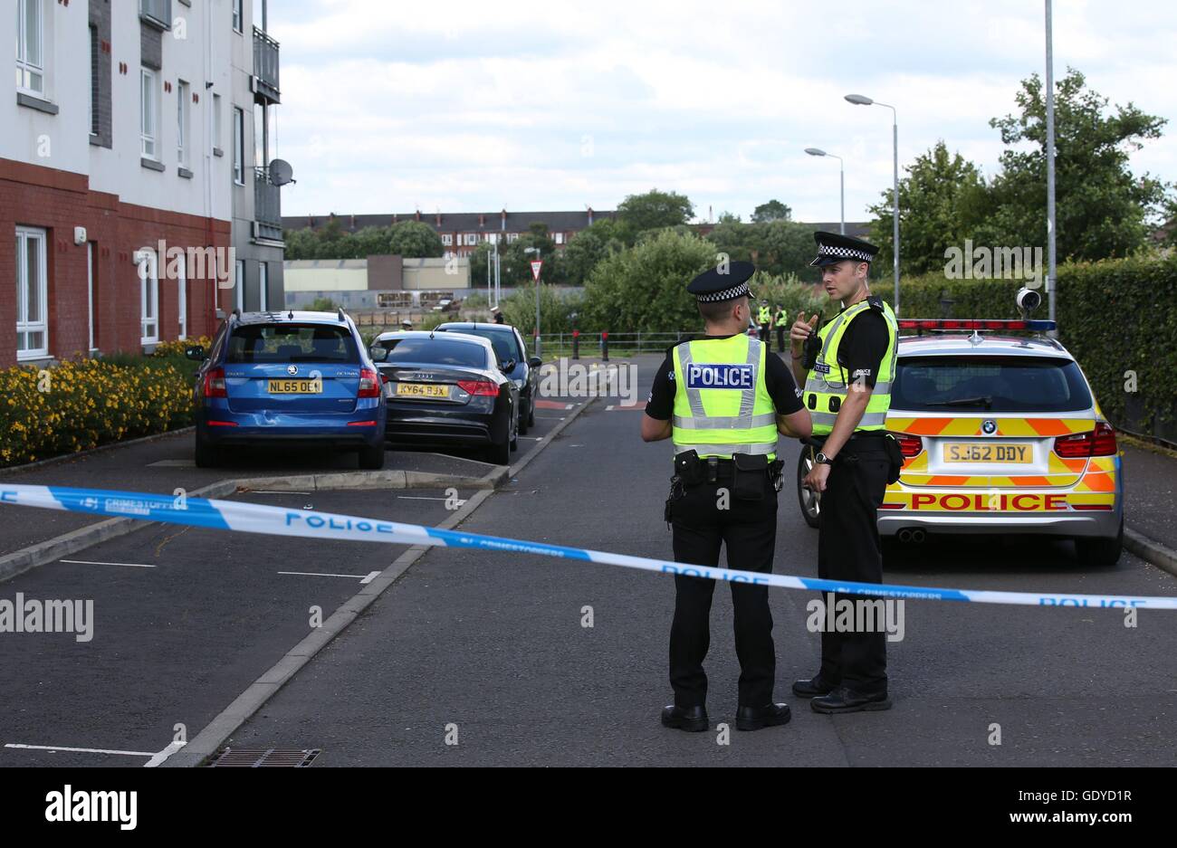 Police officers in Renfrew near to the scene where a body was recovered after a car plunged into the River Clyde. The blue Skoda (left) was partly hit by the car before it entered the water. Stock Photo