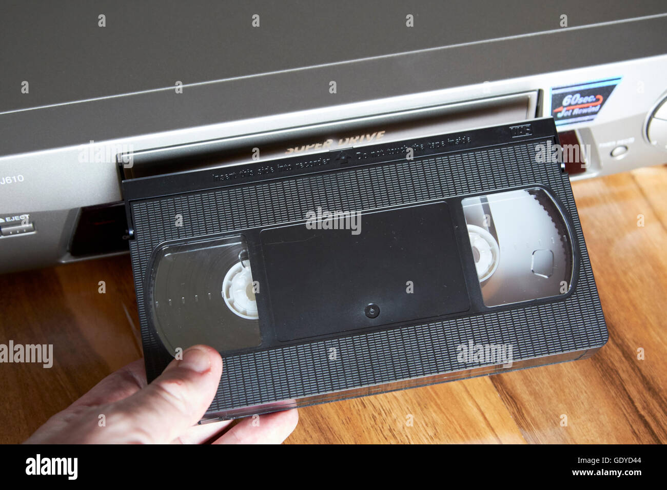 mans hand inserting VHS blank cassette tape in a VHS player Stock Photo