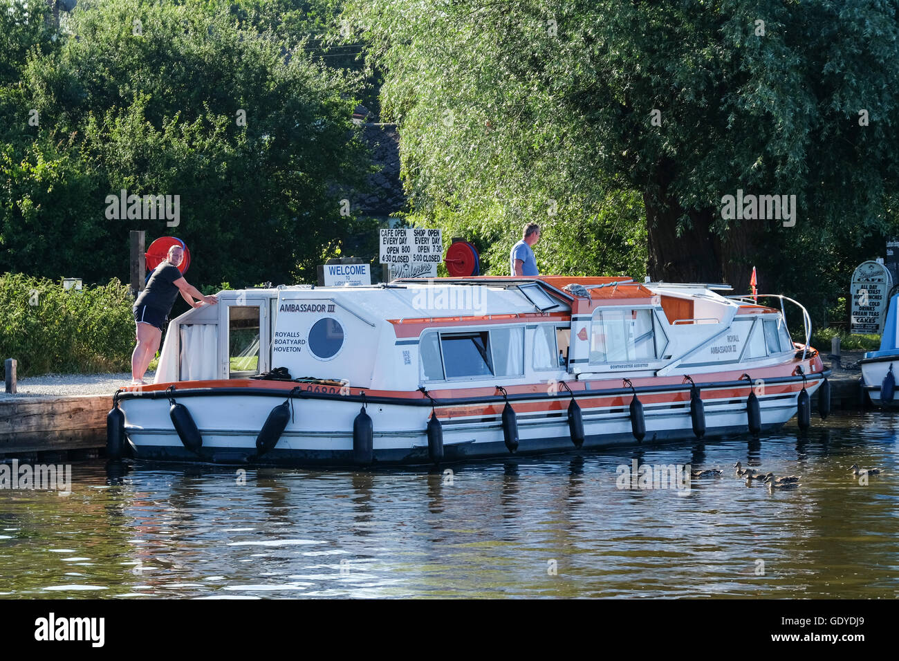 A boat prepares to leave its Ludham Bridge mooring on the Norfolk Broads Stock Photo