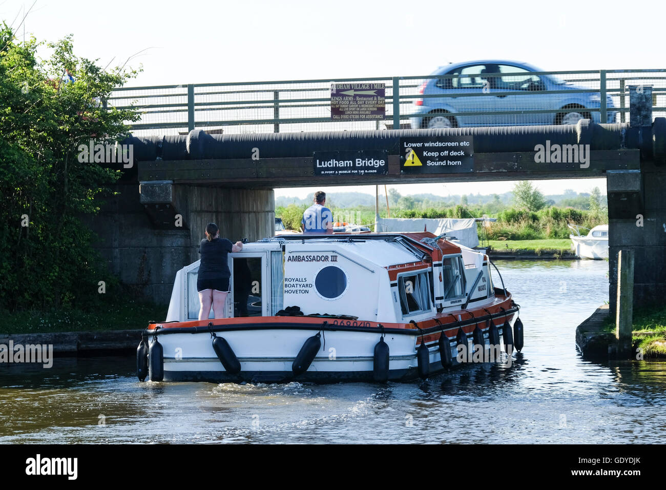 A pleasure cruiser navigates under the low Ludham Bridge on the Norfolk Broads Stock Photo