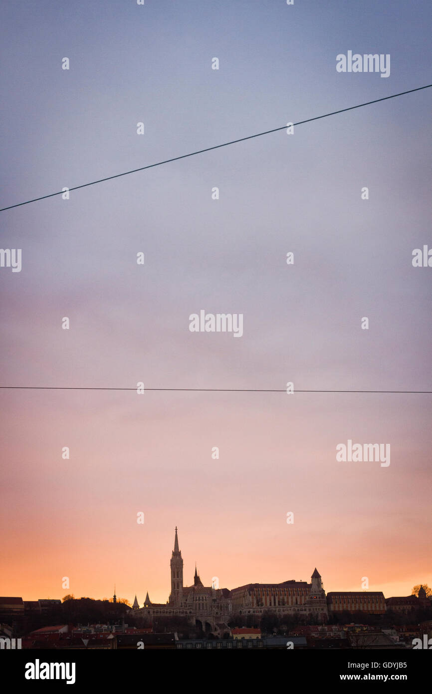 The silhouetted spire of a church on Budapest's skyline during sunset ...