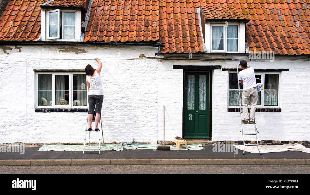 Painting a traditional white cottage Stock Photo