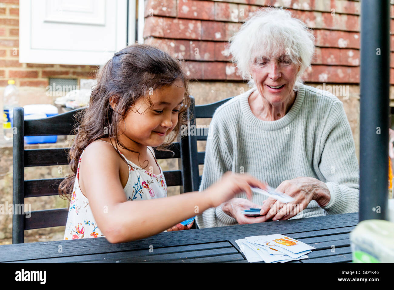 A Mixed Race Child Plays Snap With Her Grandmother, Sussex, UK Stock Photo