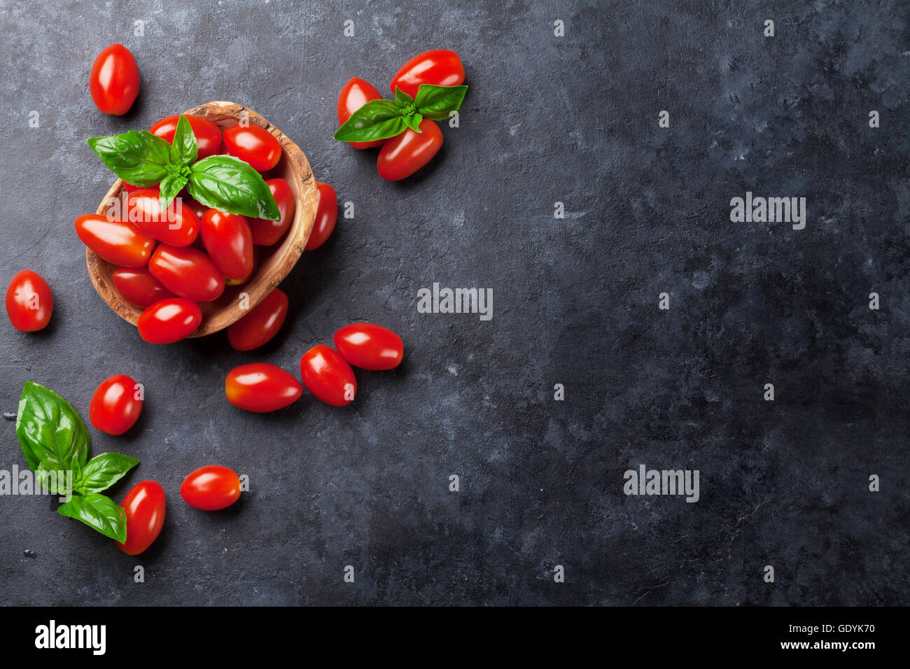 Tomatoes and basil herb leaves over stone table top view hi-res stock ...