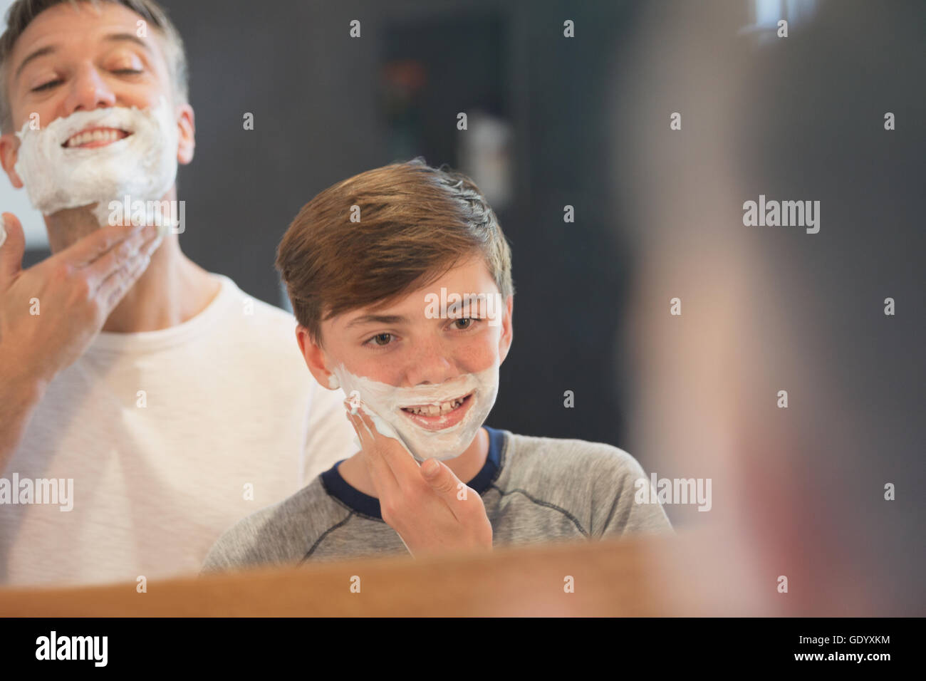 Father watching son pretending to shave face in bathroom mirror Stock Photo