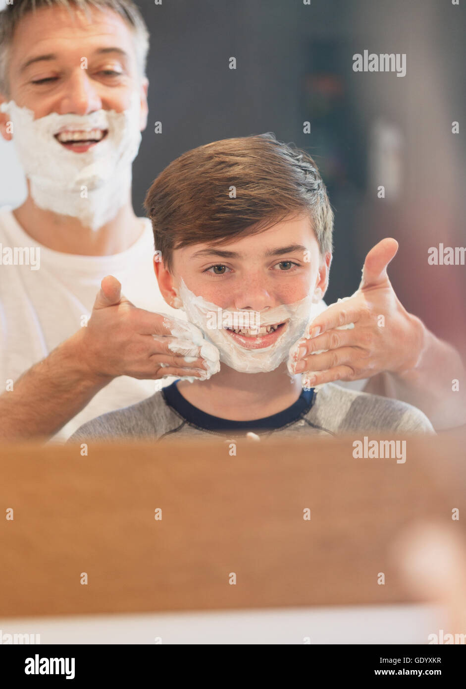 Father helping son pretending to shave in bathroom mirror Stock Photo