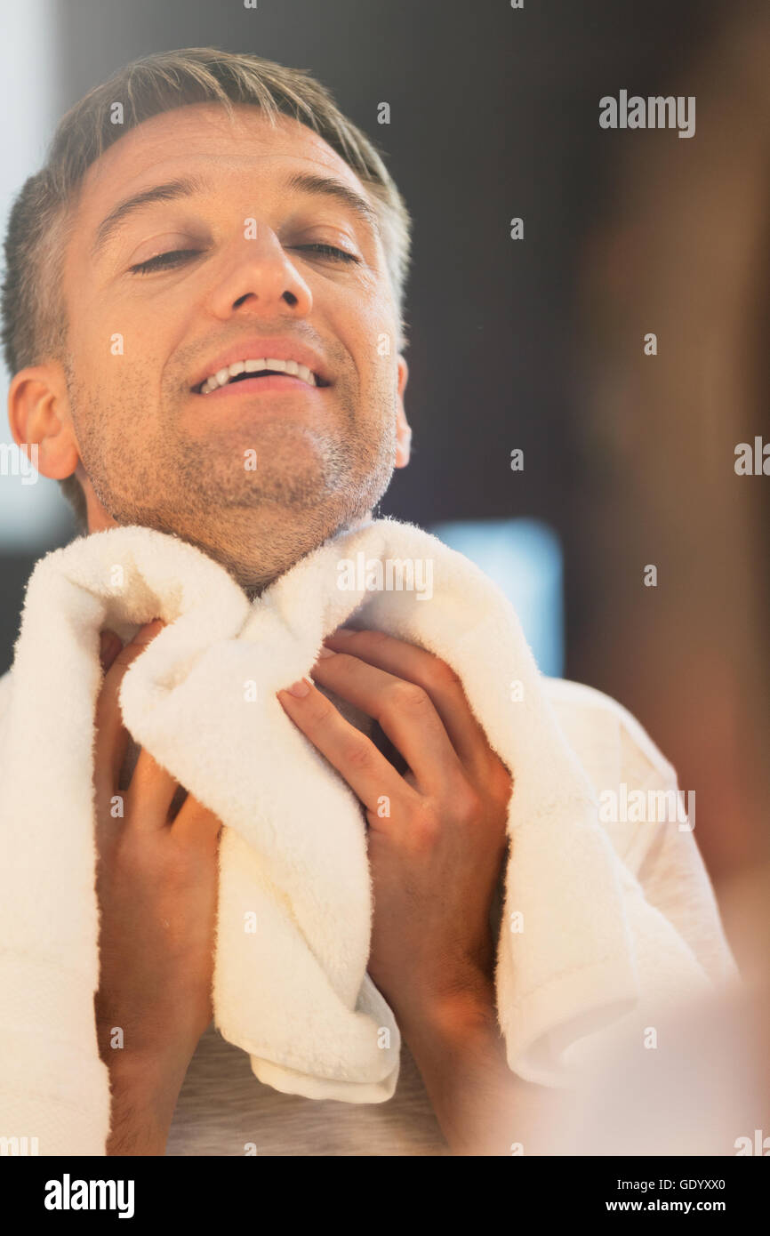 Man wiping neck at bathroom mirror Stock Photo