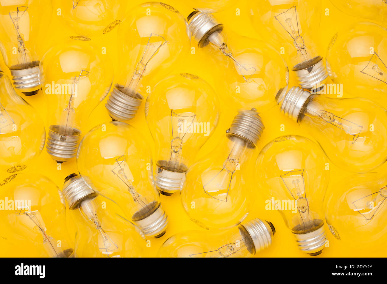Lots of transparent lightbulbs against yellow Stock Photo