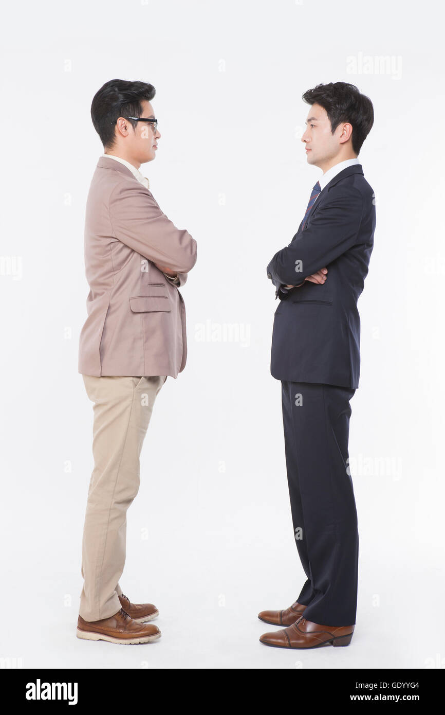 Side view of two business men standing face to face with their arms folded Stock Photo