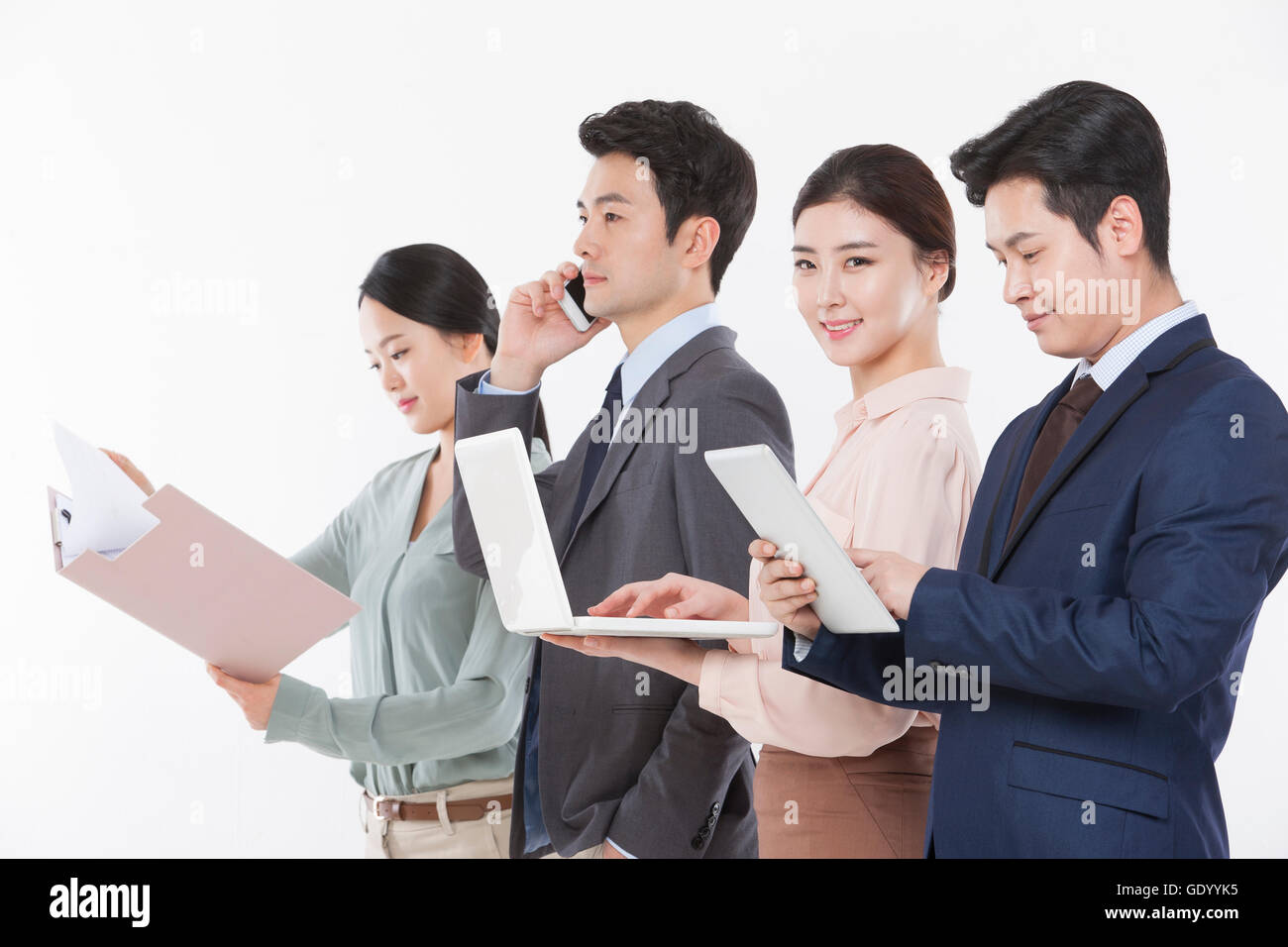Business woman with a notebook computer smiling at front and three business people with file, cellphone and tablet looking down Stock Photo