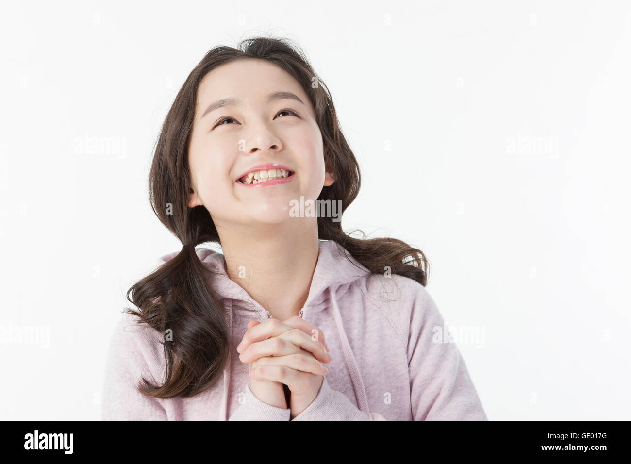 Portrait of smiling school girl folding her hands looking up Stock