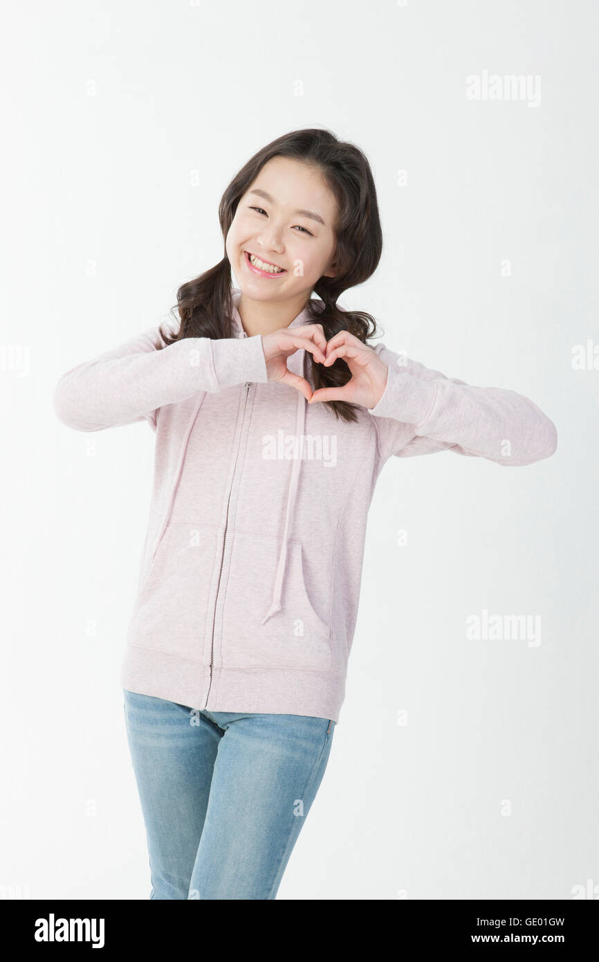Smiling twelve-year-old girl in casual clothes making a heart with her fingers Stock Photo