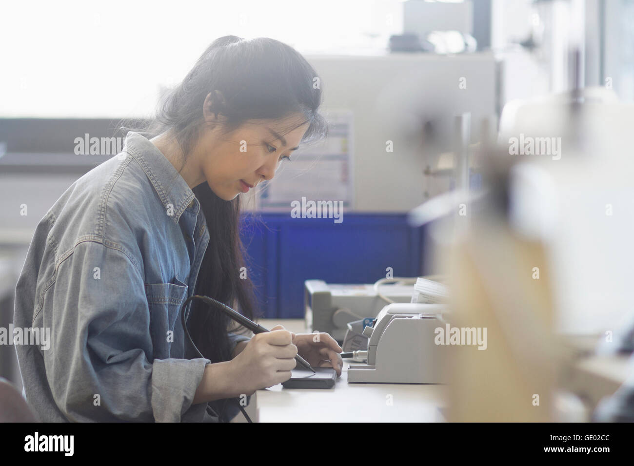 Female technician soldering electronic components in an industrial plant, Freiburg Im Breisgau