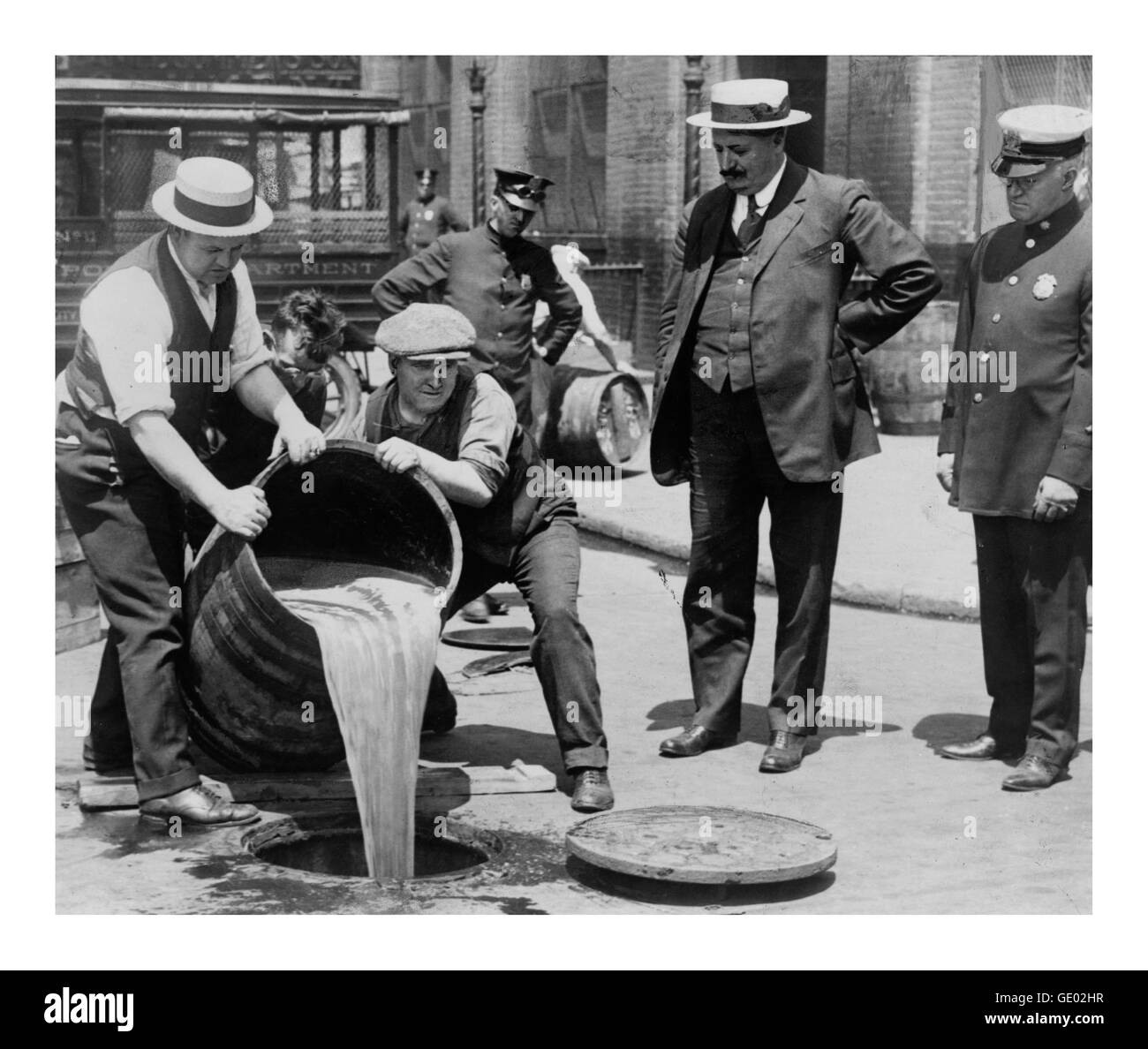 PROHIBITION Alcohol is being poured out of a barrel down the sewers, monitored by the police and federal officers, during American 1919 prohibition laws and bootlegging days in the USA Stock Photo