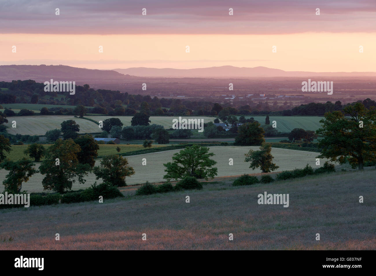 View over farmland and Vale of Evesham with Bredon Hill and Malvern Hills in distance at sunset Stock Photo