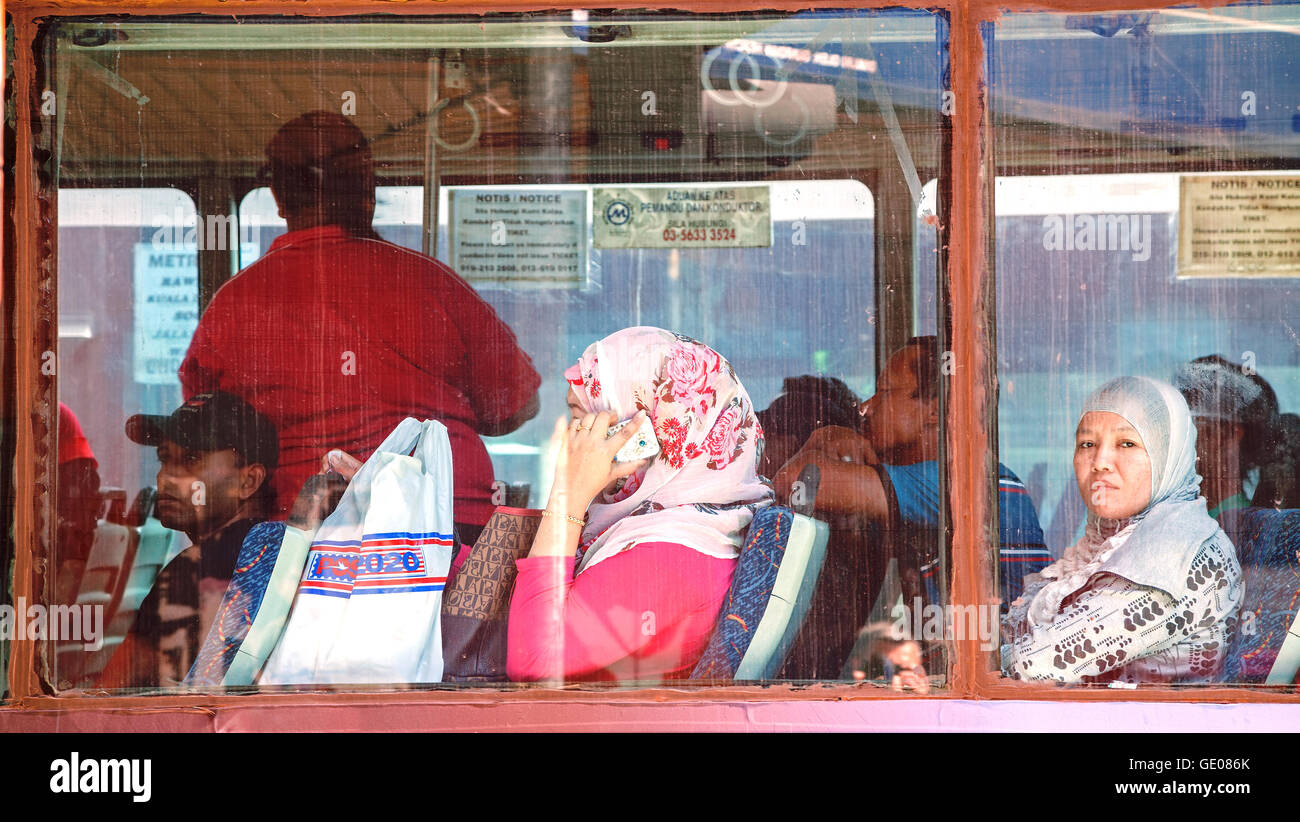 Passengers of city bus seen through dirty window. Stock Photo