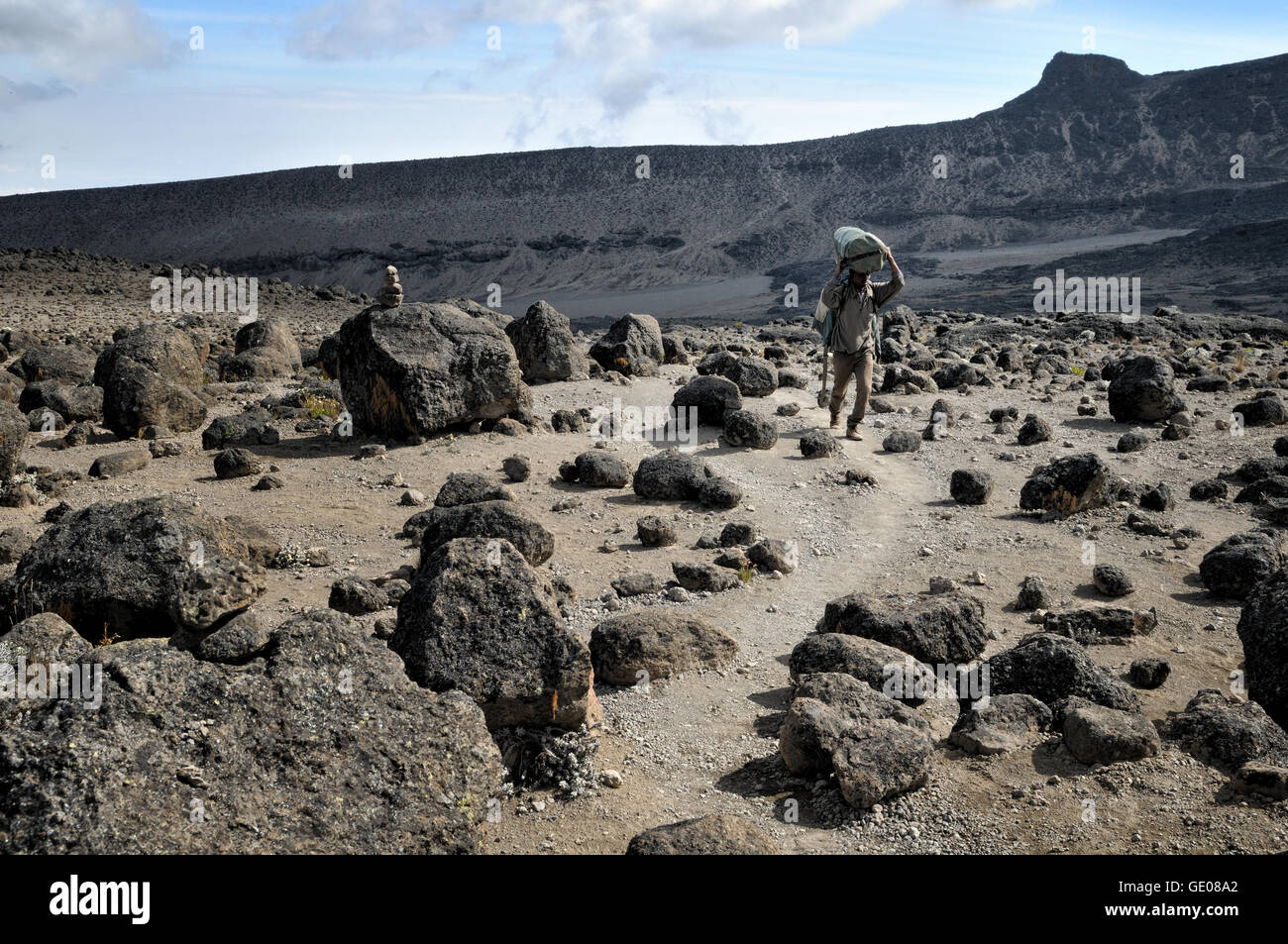 Porter and volcanic rocks, Mount Kilimanjaro National Park, Tanzania Stock Photo