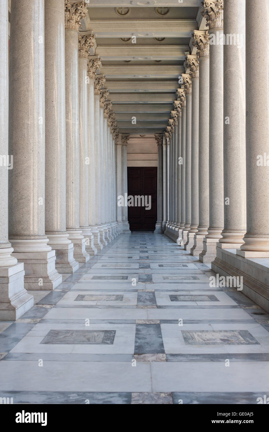 Path between classic architecture colonnade with dark door at the end, symbol of unknown and mystery Stock Photo