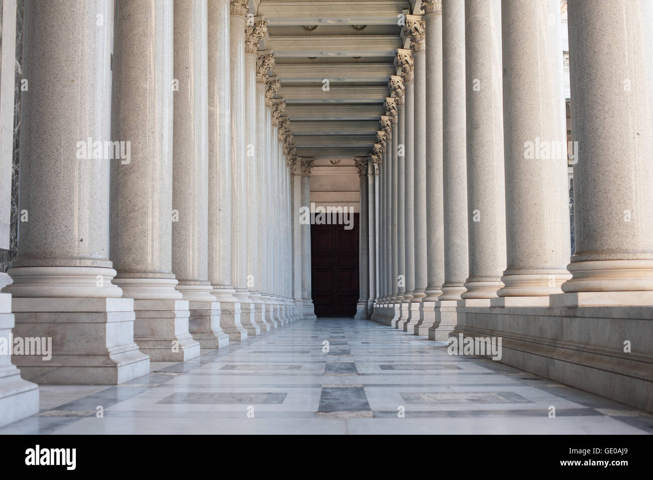 Path between classic architecture colonnade with dark door at the end, symbol of unknown and mystery Stock Photo