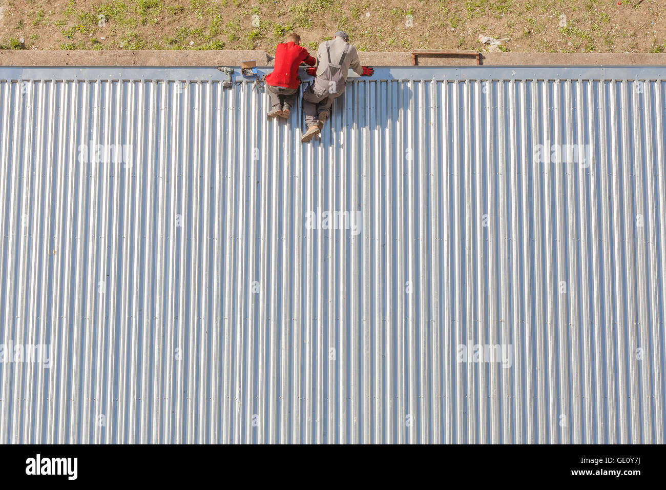 Szczecin, Poland - April 07, 2016: Workers repairing a store roof made of corrugated metal sheets, picture taken from above. Stock Photo