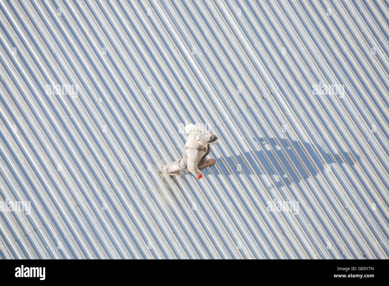 Man inspecting a store roof made of corrugated metal sheets after repair, picture taken from above. Stock Photo