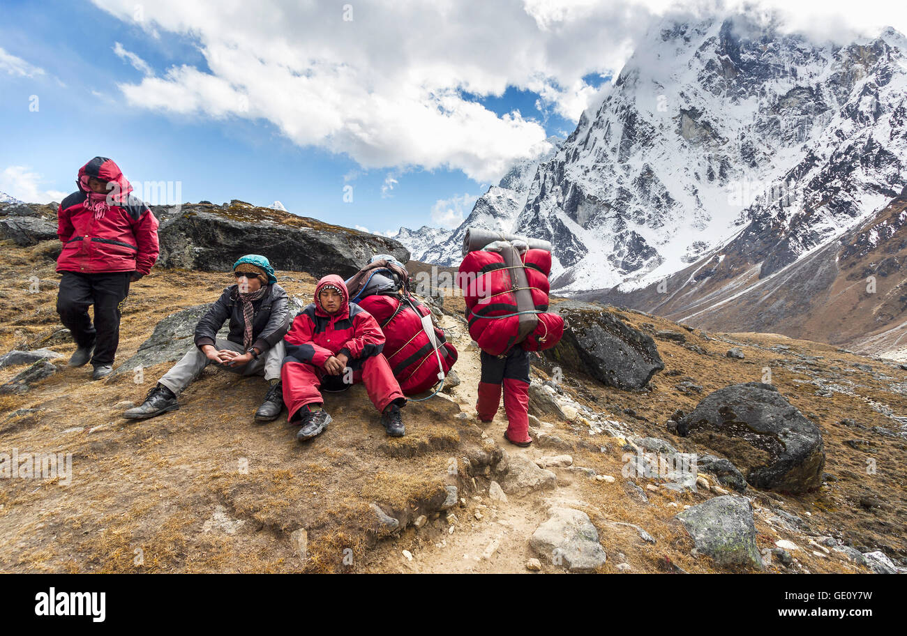 Porters with heavy load after crossing Cho La Pass in Himalayas, located 5,420 meters (17,782 ft) above sea level in Solukhumbu. Stock Photo