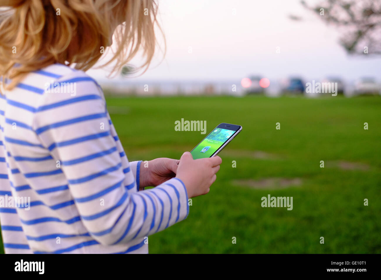 Young child playing Pokemon Go outdoors in a park Stock Photo