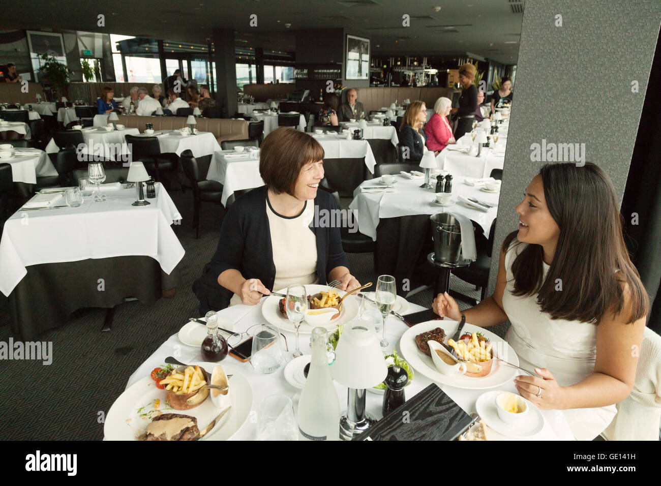 Restaurant two people eating; Two women eating a meal, interior, Marco Pierre White Steakhouse restaurant,  Birmingham UK Stock Photo