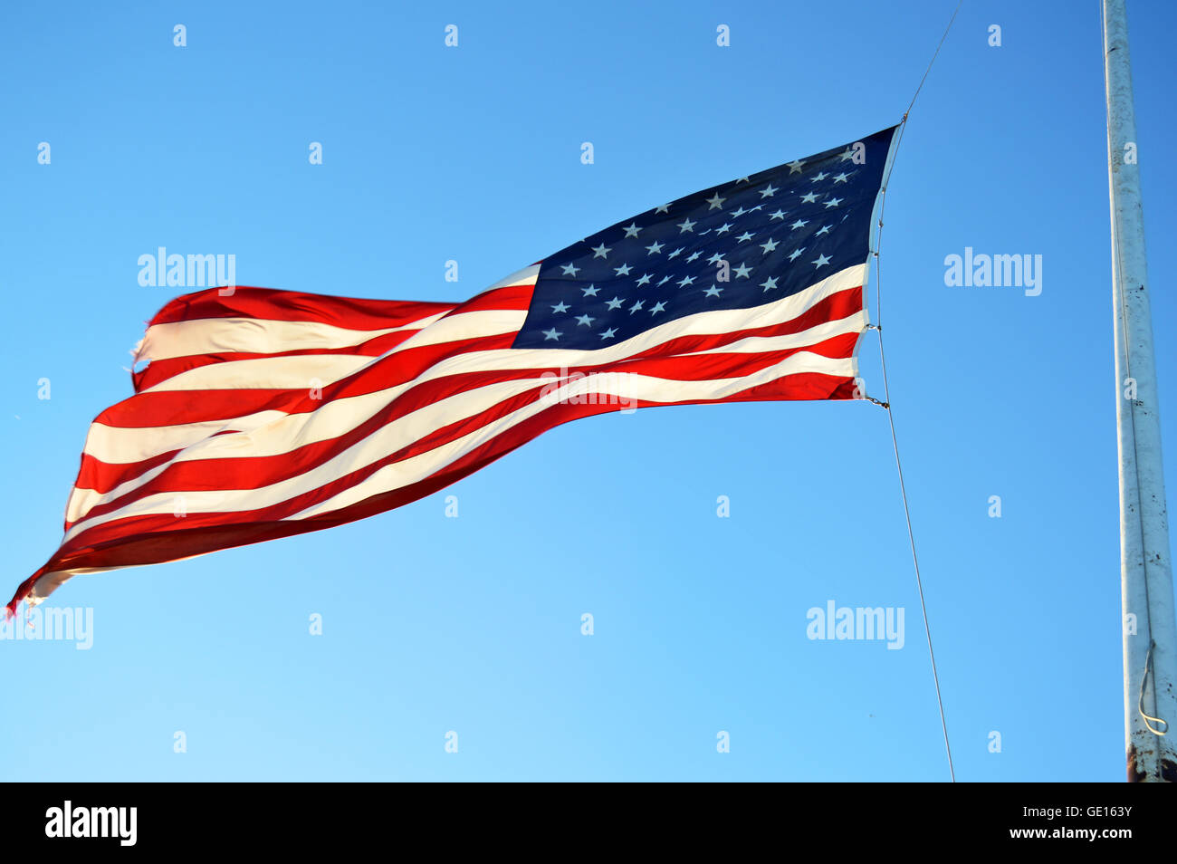 United States flag against blue sky Stock Photo - Alamy