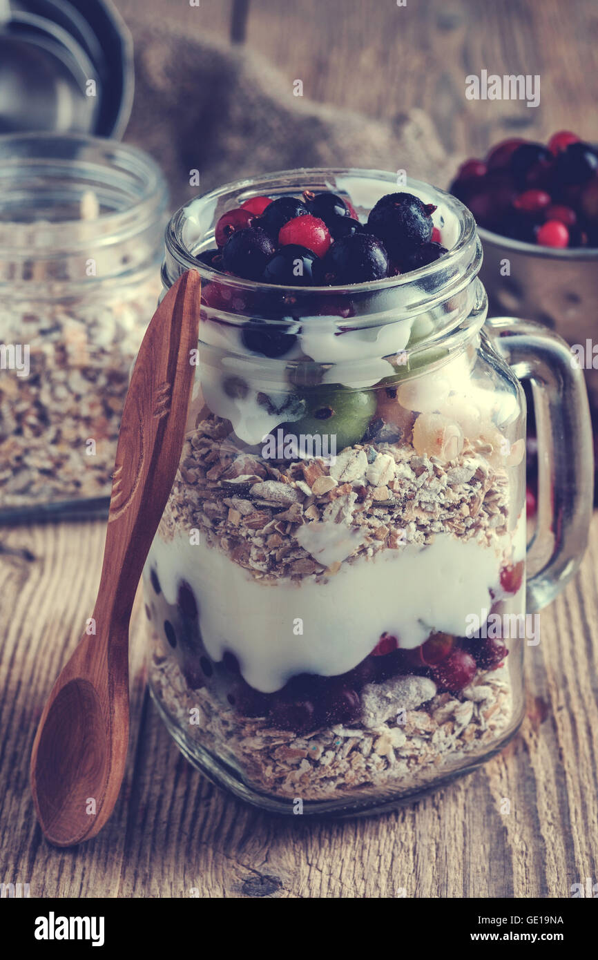 Healthy breakfast with Homemade granola. Muesli, fresh berries and yogurt in glass mason jar on wooden table. Muted colors. Inst Stock Photo