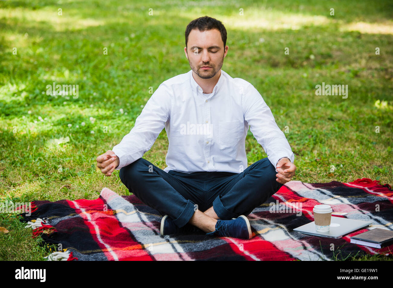 Business man relaxing in a park in the lotus position Stock Photo