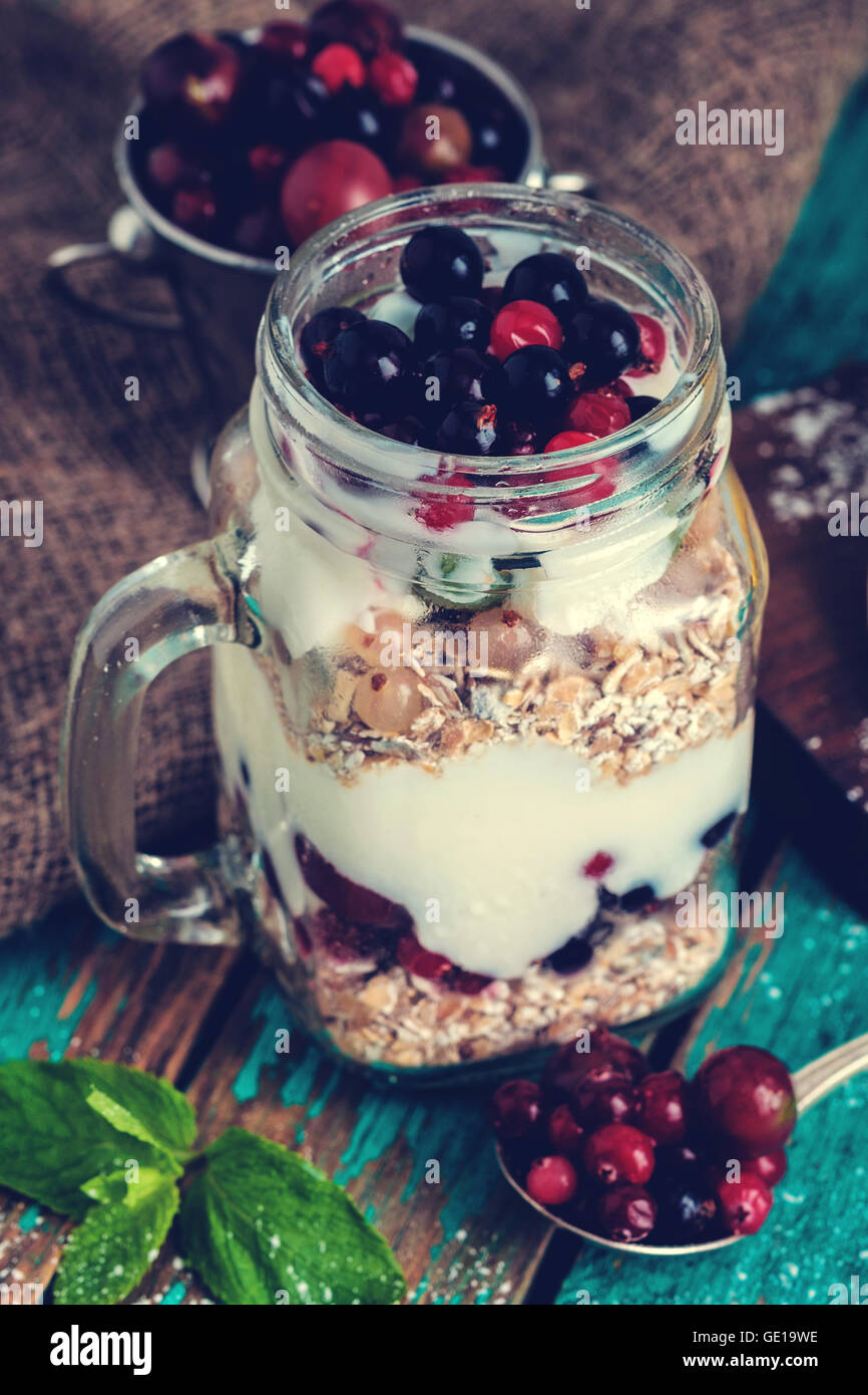 Muesli, fresh berries and yogurt in glass mason jar on wooden table. Healthy breakfast with Homemade granola. Muted colors, inst Stock Photo