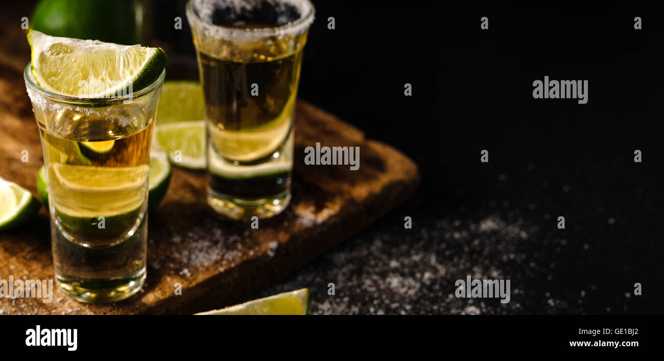 Two Gold tequila shots with lime, copy space on right side. Gold ...