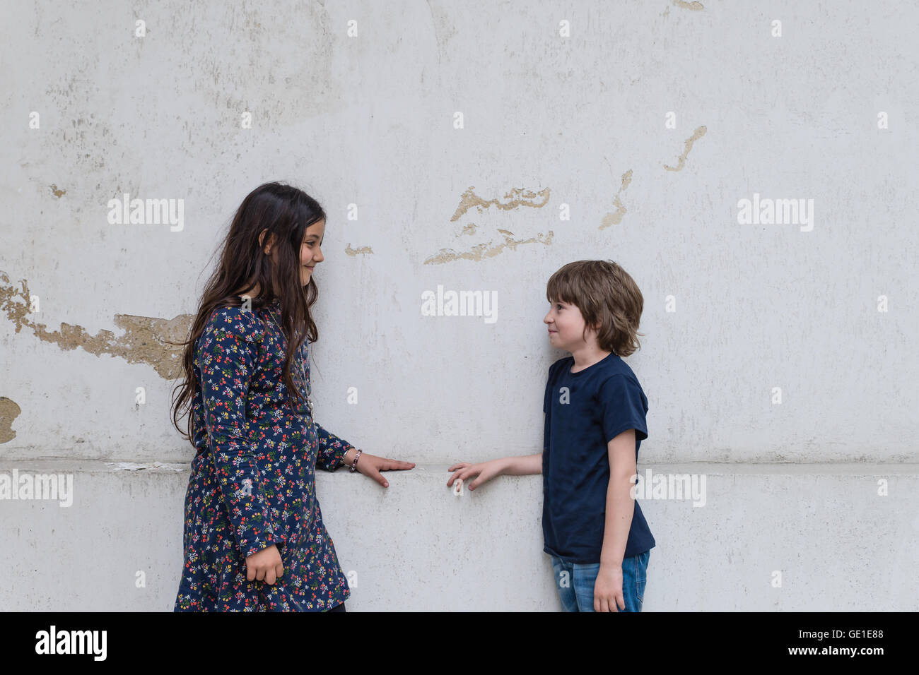 Boy and girl standing by wall looking at each other Stock Photo - Alamy