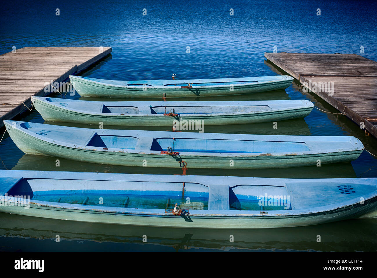 Rowing boats in a row moored at jetty Stock Photo