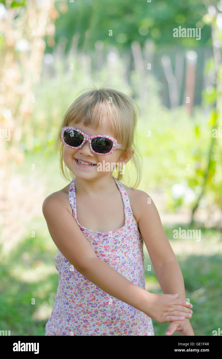 Portrait of smiling Girl standing in garden wearing sunglasses Stock ...